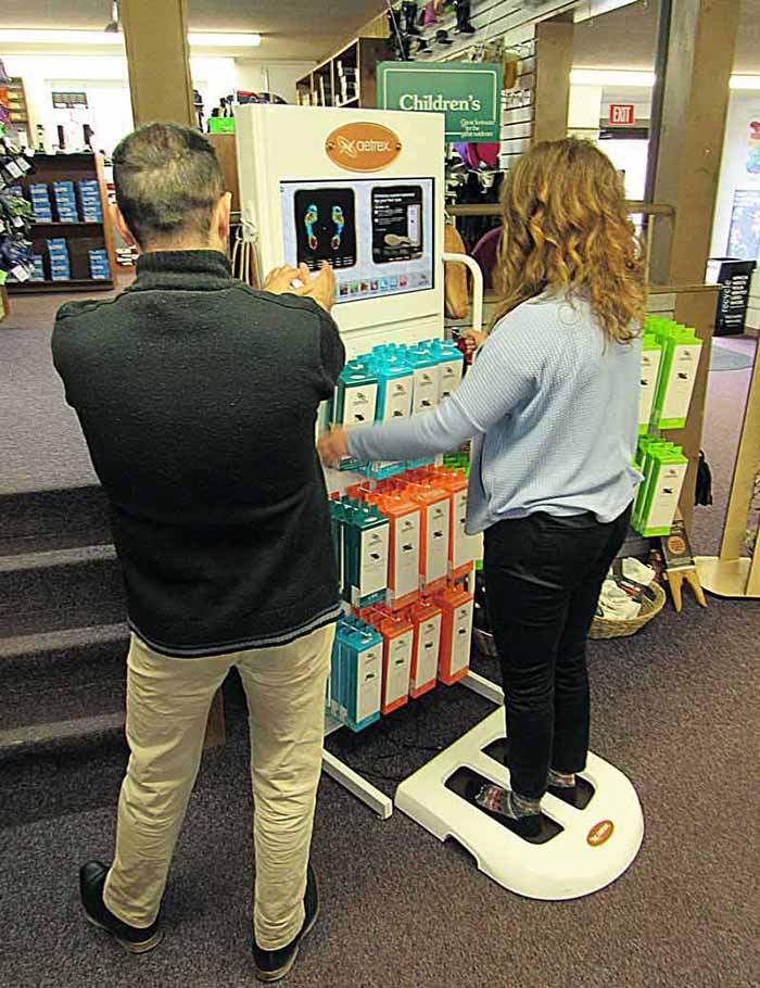 A Family Footwear Center Employee helps Customers use a Foot Scanner 