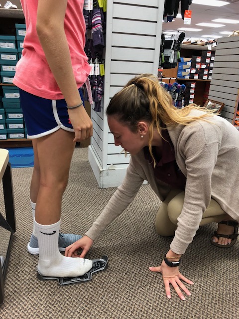 Family Footwear Center Employee Professionally Measuring a Customer's Foot.