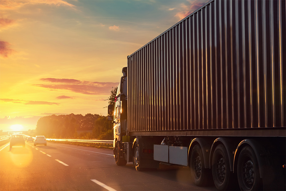 Tractor Trailer driving into the sunset on its way to a warehouse.